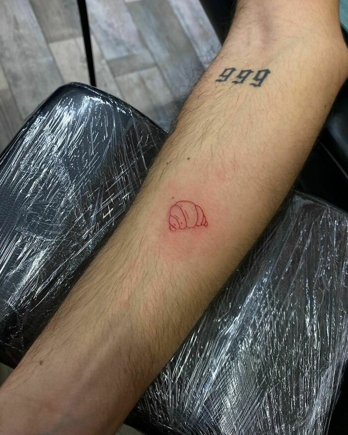 minimalistic tattoo of a red ink croissant 