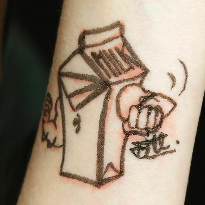 Funny tattoo of a milk carton with cartoonish hands and facial features on an arm.