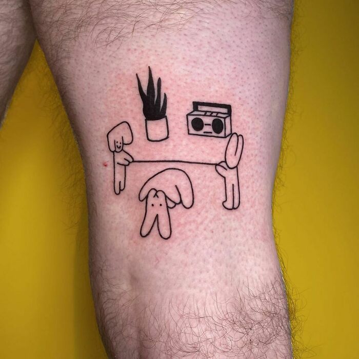 Funny tattoo of cartoon figures holding a table with a plant and boombox.