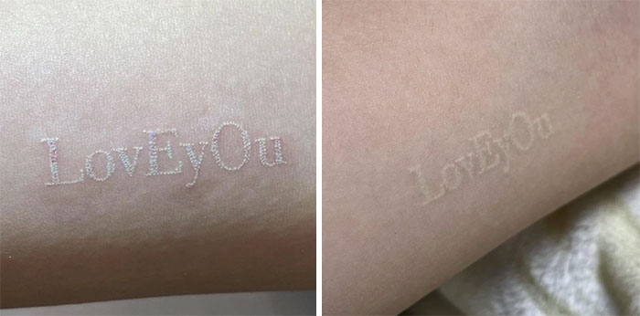 Aged tattoo with faded white ink reading "LovEyOu" on skin, showing changes over time.