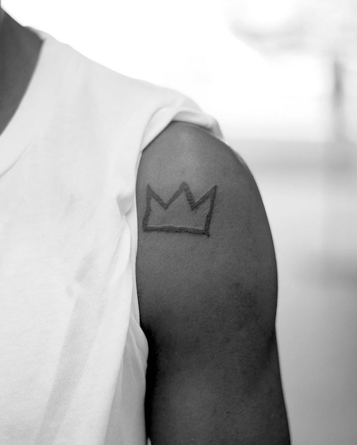 Tattoo of a crown symbol on a person's arm in black ink, showcasing celebrity tattoos style.