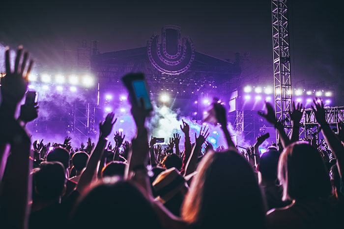 Crowd at a live music concert with raised hands and glowing stage lights showcasing big trends in entertainment events.