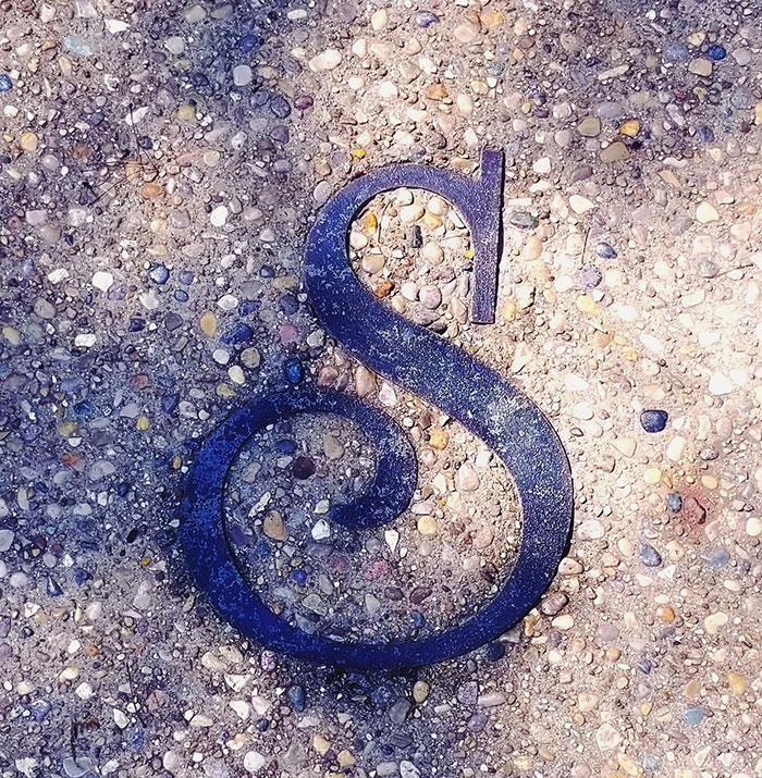 Decorative metal ampersand on textured stone surface highlighting big trends in design and style.