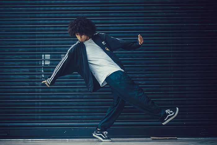 Young man in retro streetwear performing a dance move representing big forgotten trends in urban fashion.