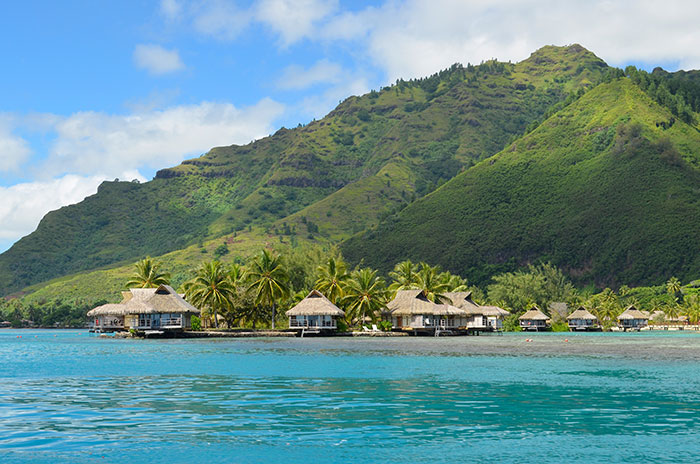 Luxury thatched roof bungalows by the blue ocean and green mountains