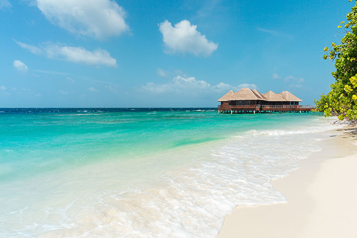 Beach with white sand, ocean, and water bungalows