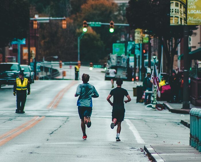 Two Men Running A Marathon In The Street 