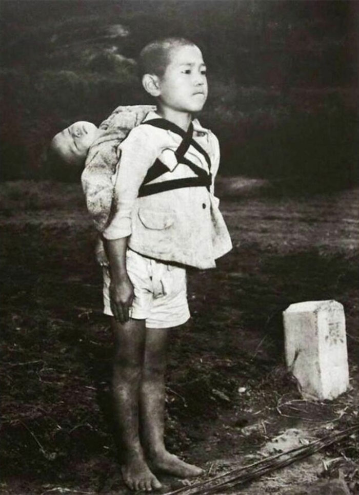 1945. Un estoico niño japonés de 10 años permanece atento tras llevar a su hermano menor muerto a la pira crematoria, Nagasaki