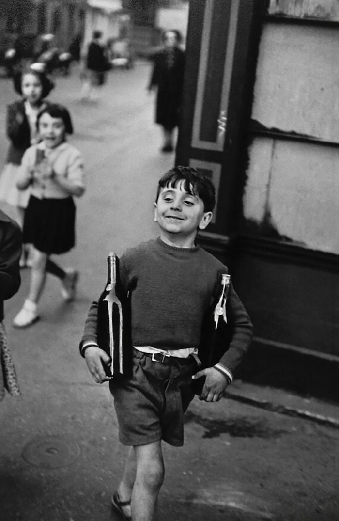 1954. A Young Boy Carrying Two Bottles Of Wine Under His Arms, Rue Mouffetard, Paris. Photo By Henri Cartier-Bresson
