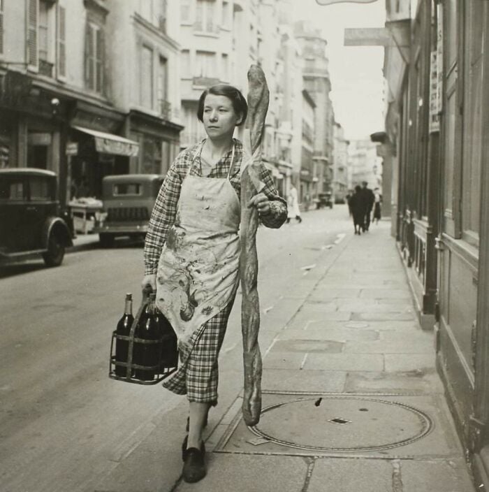 Una francesa con su baguette y seis botellas de vino. París, Francia, 1945 