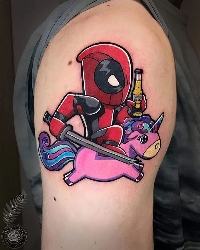 Colorful Deadpool on a unicorn arm tattoo 