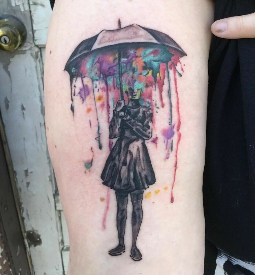 woman staying with an umbrella in her hands tattoo on the arm