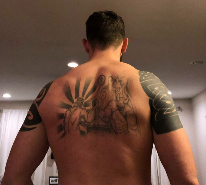 Funny tattoo of arm wrestling scene on man's back, playful expression reflecting humor in body art.