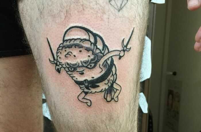 Funny sushi ninja tattoo on leg, showcasing playful design with a sushi character holding swords in a ninja pose.