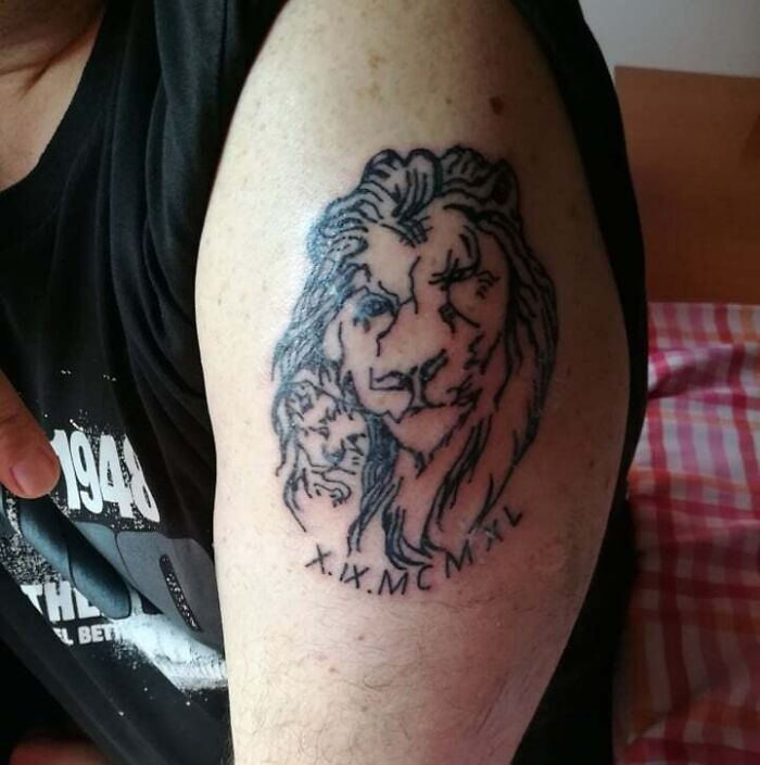 Funny bad lion tattoo on arm with Roman numerals below.