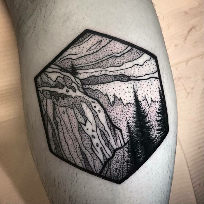 Hexagonal nature tattoo featuring mountains and pine trees on a person's leg.