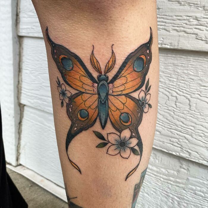 Butterfly tattoo with floral elements on a person's leg, showcasing nature tattoos for those with a wild side.