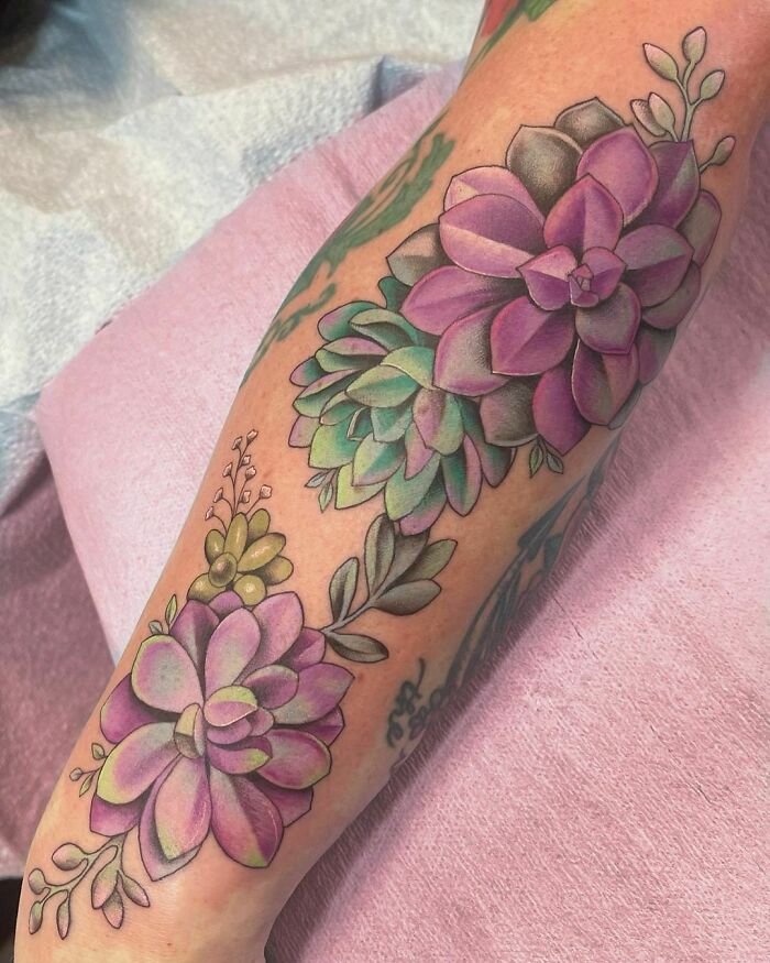 Colorful nature tattoo of vibrant purple and green succulents on arm.