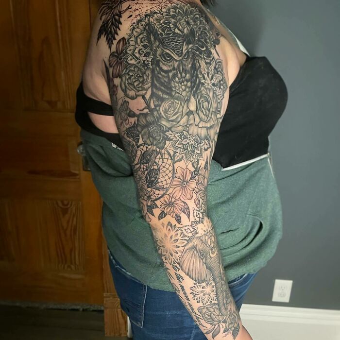Detailed nature tattoo sleeve featuring an owl and floral designs on a person's arm.