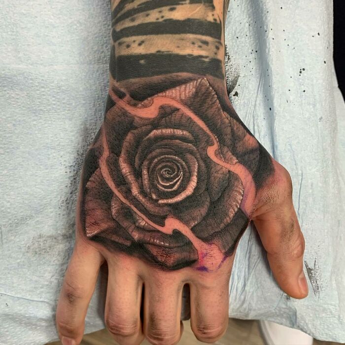 Hand tattoo featuring a detailed black and gray rose design, embodying nature tattoos and a wild side.