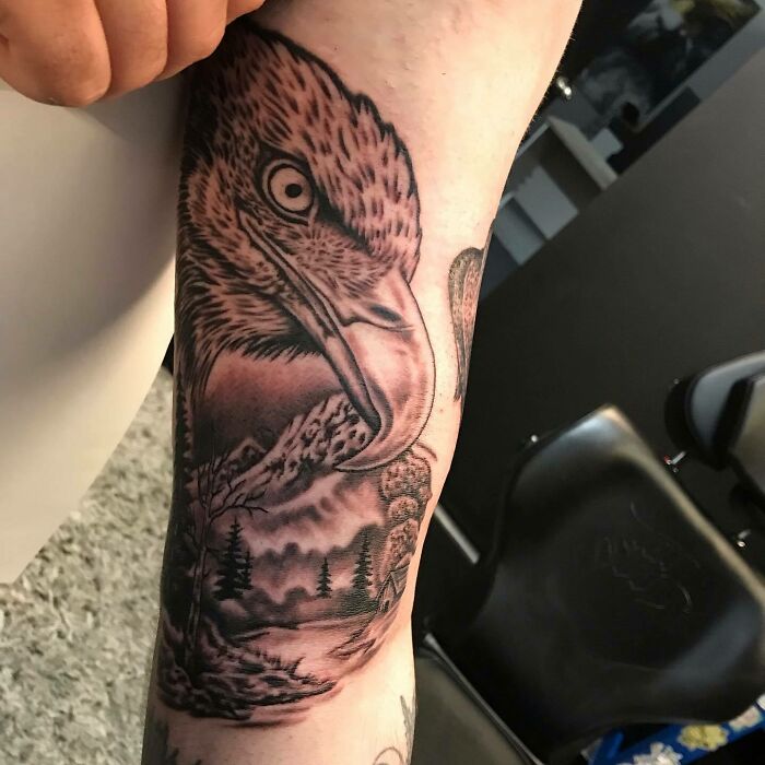Eagle nature tattoo on arm, featuring detailed landscape and wildlife elements.