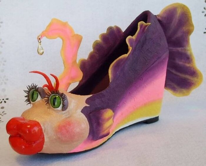 Weird shoe resembling a colorful fish with large green eyes, red lips, and a decorative fin design.