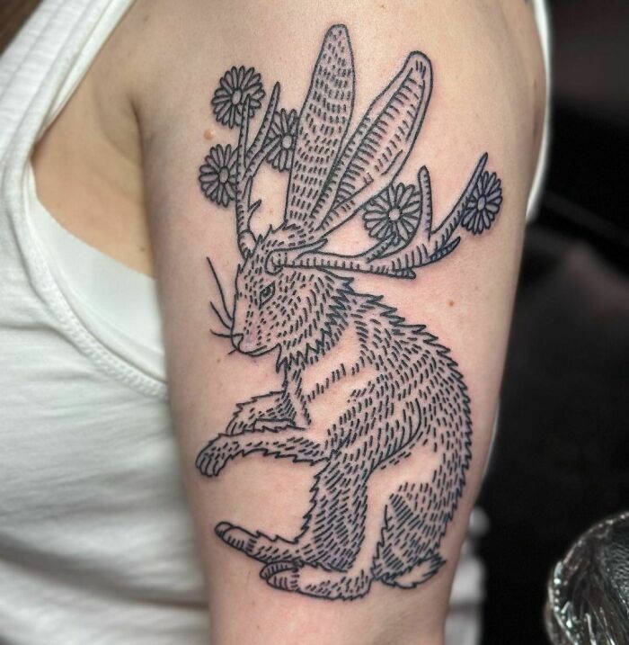 Unique nature tattoo of a jackalope with floral antlers on an upper arm.