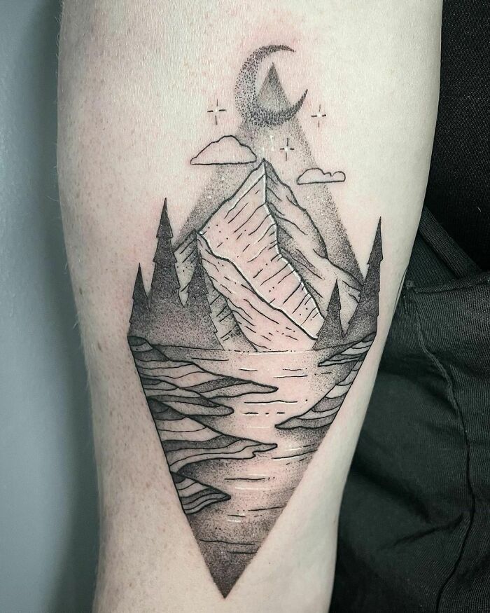 Triangle-shaped tattoo of mountains and forest under a crescent moon, perfect for nature enthusiasts.