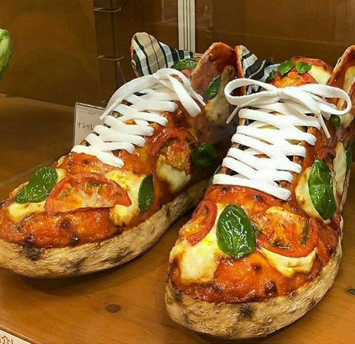Weird shoes in a bizarre pizza design with tomatoes and basil toppings, featuring white laces.