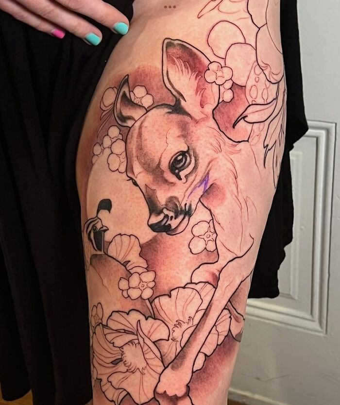 Deer nature tattoo on thigh with floral accents and bold outlines.