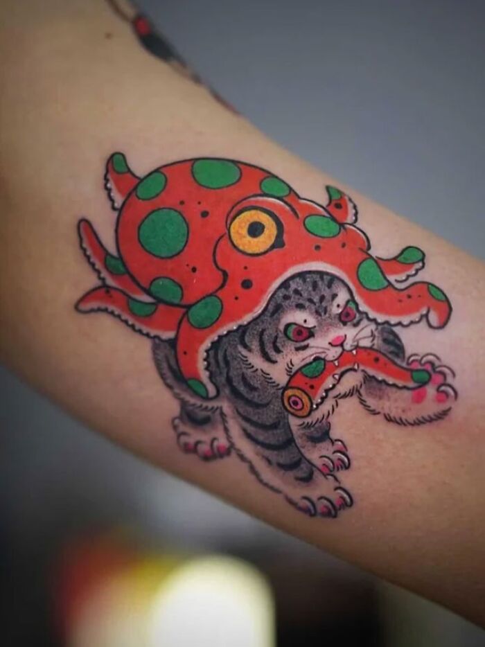 Cat and red octopus with green spots on its back tattoo