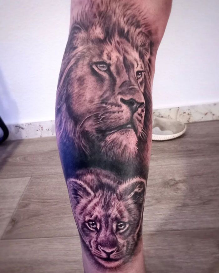 Realistic lion with a baby lion tattoo on leg