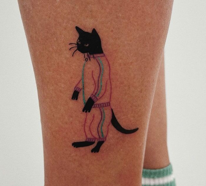 Standing black cat in sports wear tattoo on leg
