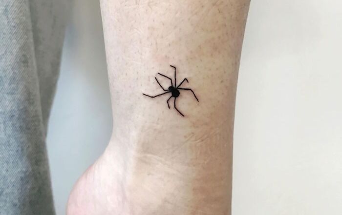 Small spider tattoo on ankle, minimalist animal tattoo design.