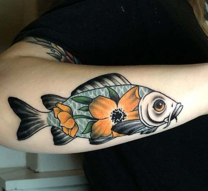 Colorful fish tattoo design on forearm with floral detail, showcasing unique animal tattoo art.