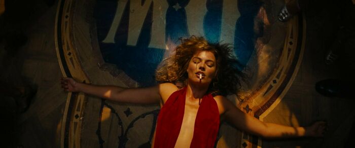 Nellie wearing red dress lying on the floor with cigarette 