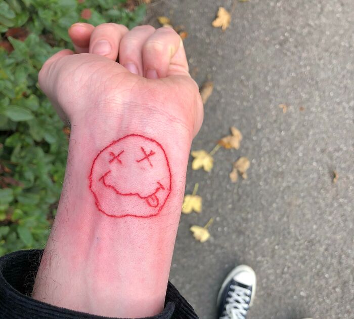 Red drunk face wrist tattoo 