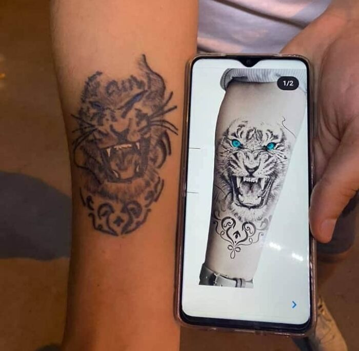 Funny tattoo of a tiger on an arm, next to a phone displaying the intended design.