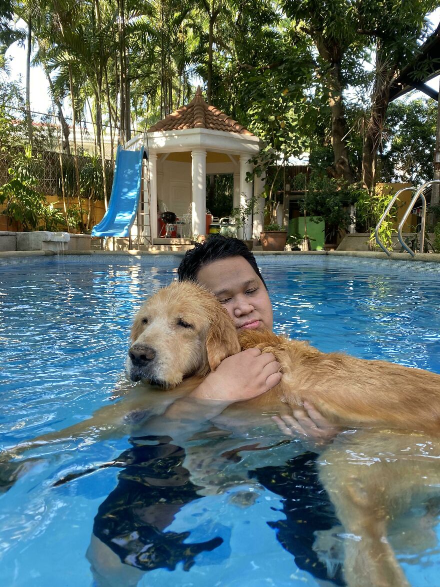 man holding his dog in arms in the swimming pool