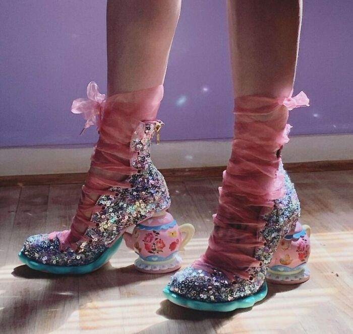 Sparkly shoes with teacup heels and pink ribbon laces showcase a quirky, artistic design.