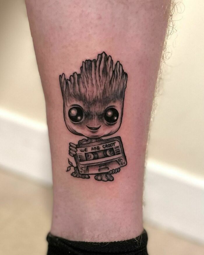 Groot tattoo on leg featuring a cassette tape with the words "We Are Groot," representing Marvel superhero theme.