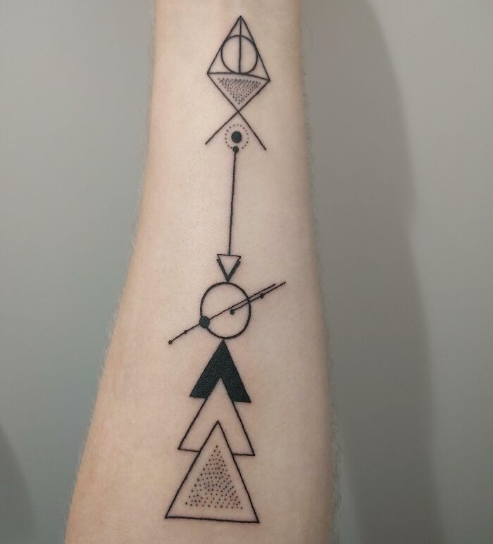 Geometric tattoo on forearm featuring triangles, circles, and lines in a minimalist style.