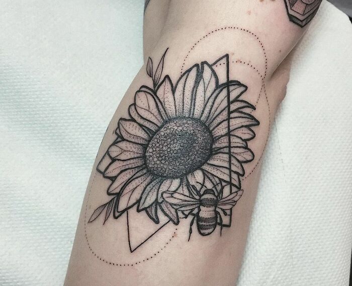 Geometric tattoo of a sunflower and bee with dotted and triangular design elements.