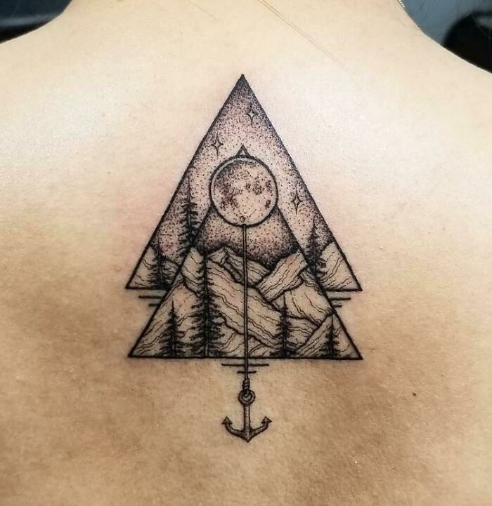 Geometric tattoo with triangle design, featuring mountains, a full moon, and an anchor, showcasing exquisite creativity.