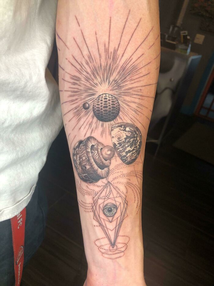 Geometric tattoo featuring cosmic elements and intricate designs on a forearm.