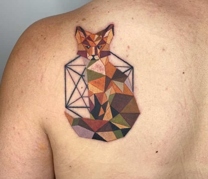 Geometric tattoo of a fox with colorful, angular shapes on a person's back.