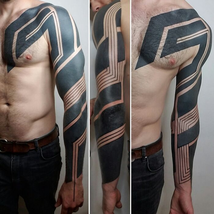 Geometric tattoos with bold black patterns covering a man's arm and shoulder.