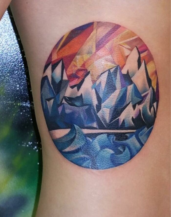 Geometric tattoo with abstract landscape design in vibrant colors on skin.