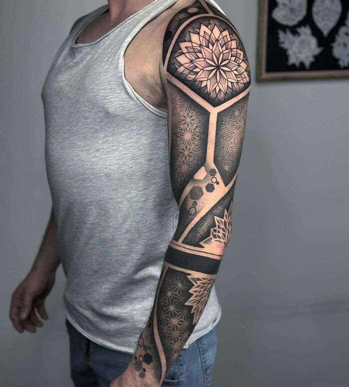 Geometric tattoo sleeve design featuring intricate patterns on an arm.