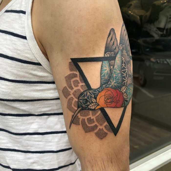 Geometric tattoo featuring a hummingbird and rose on a person's arm, highlighting intricate patterns and shapes.
